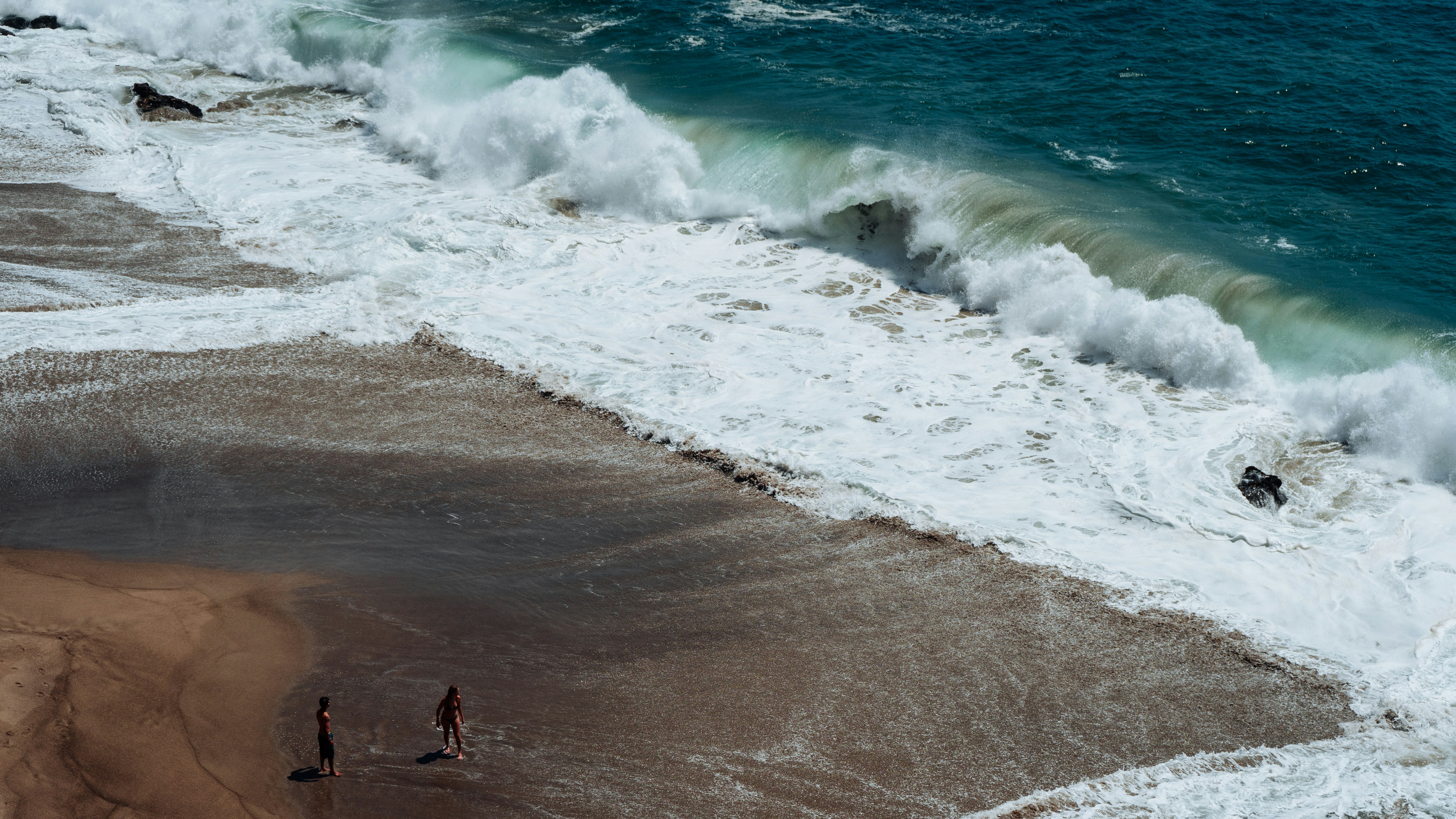 two person on seashore facing ocean waves